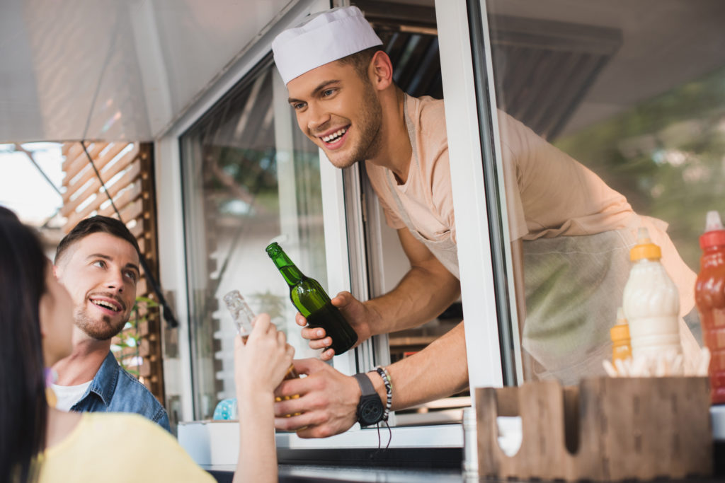 smiling chef giving drinks to customers from food truck