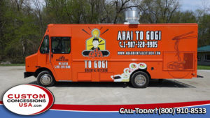 side view of an orange food truck with graphic of sushi rolls and a cartoon asian person