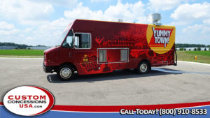 red food truck parked in an flat parking lot under a blue sky with clouds