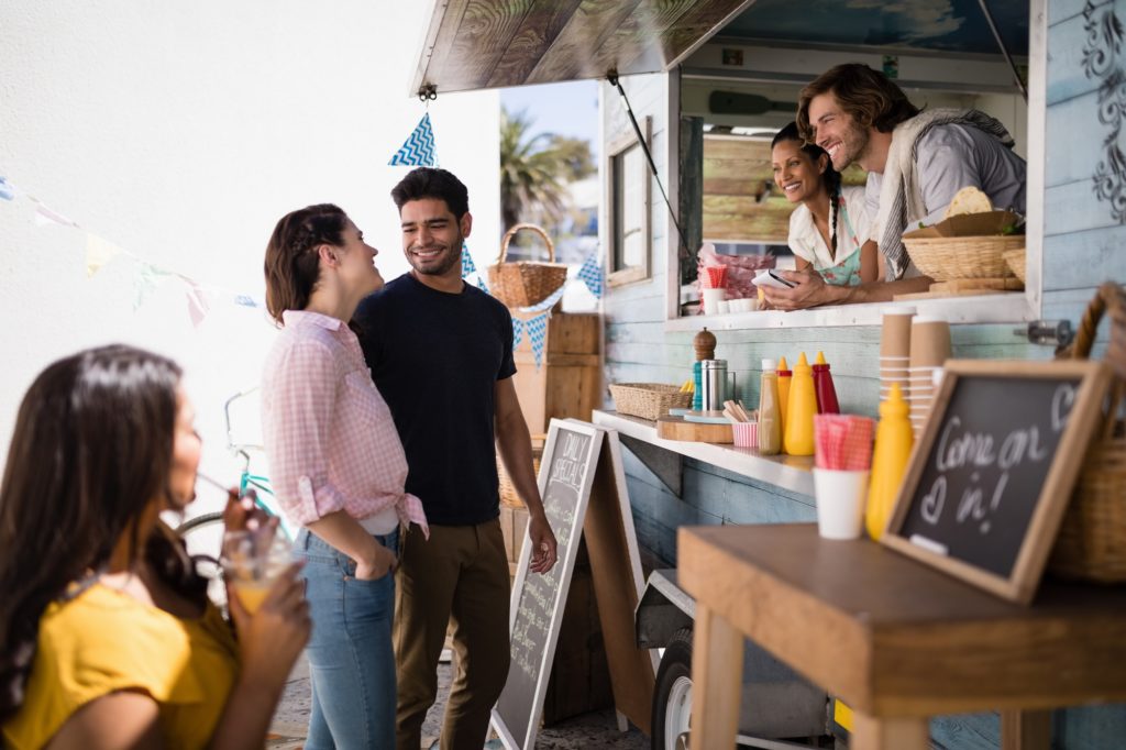 smiling couple ordering food from a food truck