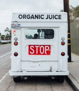 rear side of white food truck with a sign for organic juice