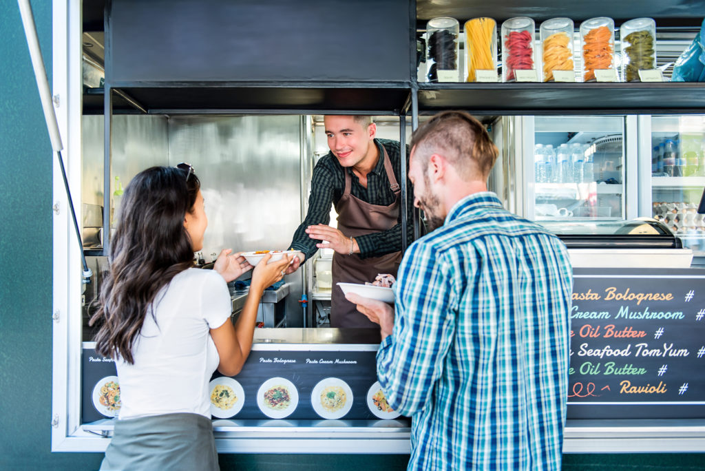 Tourist couple buys pasta from food truck vendor