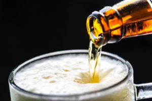 beer pouring from a bottle into a foaming mug