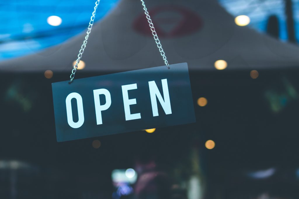 close up of an open sign hanging in a window with lights reflected in the background