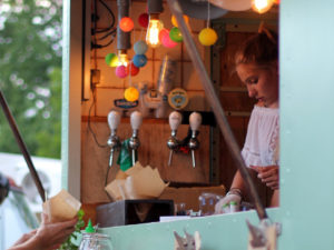 young food truck worker stands in colorful food truck scanning customer's credit card