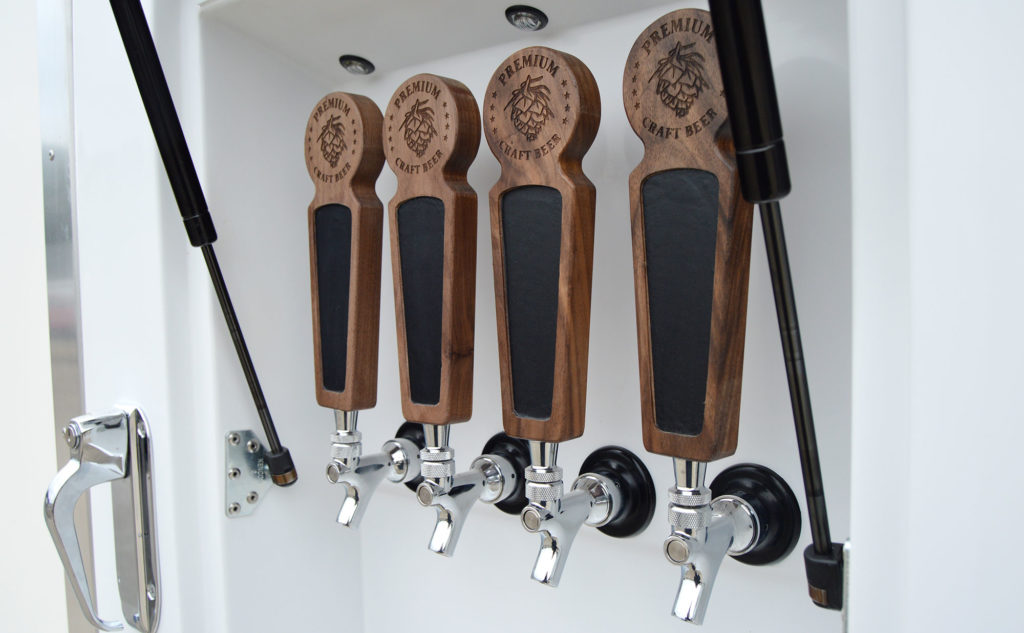 close up photo of carved wooden beer tap handles on the side of a refrigerated beer truck