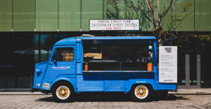 photo of a blue food truck parked on city street in front of urban building
