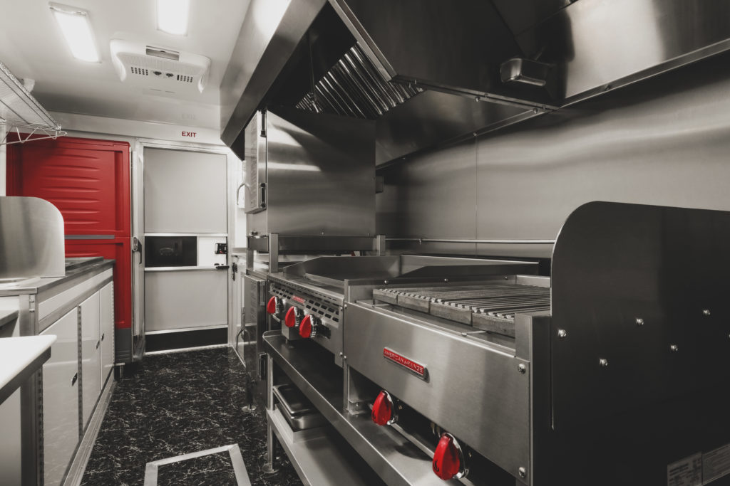 photo of a food truck interior with grill, griddle, ovens, proofing cabinet and sink