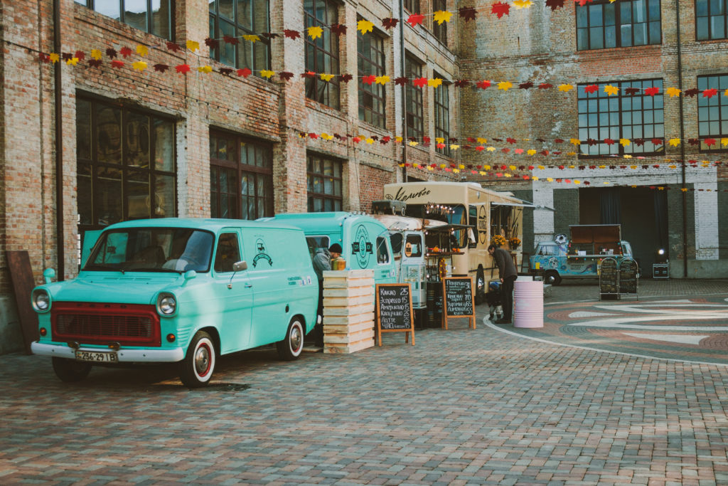 photo of several food trucks parked in a courtyard between brick buildings