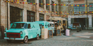 photo of several food trucks parked in a courtyard between brick buildings