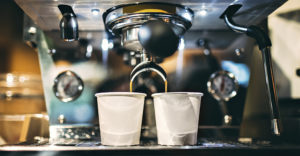 photo of a small espresso machine brewing espresso coffee into two small white cups in a coffee shop