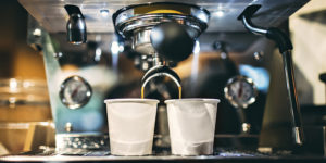 photo of a small espresso machine brewing espresso coffee into two small white cups in a coffee shop