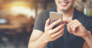 photo of a man looking down at his smartphone and smiling