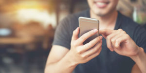 photo of a man looking down at his smartphone and smiling