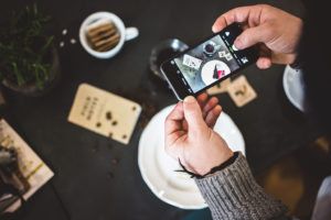 Man taking an advertising picture of coffee and cake with his phone