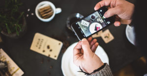 Man taking an advertising picture of coffee and cake with his phone