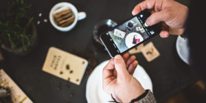 Man taking an advertising picture of coffee and cake with his phone