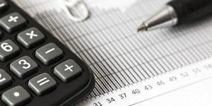 close up photo of a pen, calculator and financial charts