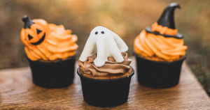 color photo of three halloween cupcakes on a wooden cutting board