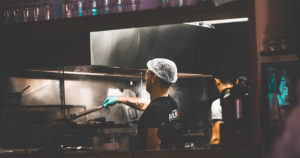 man wearing a hairnet working in a restaurant kitchen