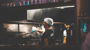 man wearing a hairnet working in a restaurant kitchen