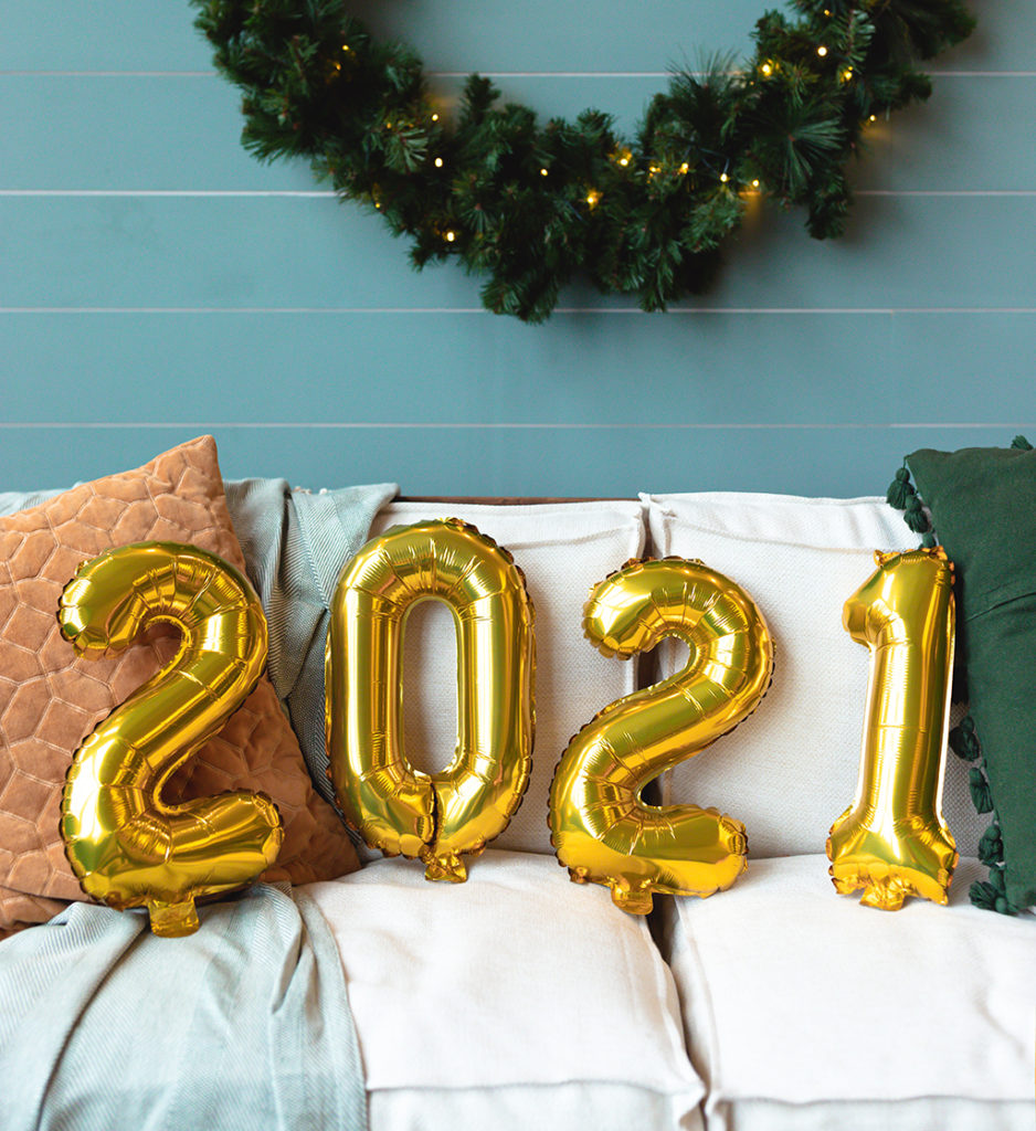photo of gold balloons spelling out 2021 on a white couch with a wreath in the background