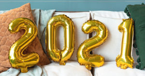 photo of gold balloons spelling out 2021 on a white couch with a wreath in the background