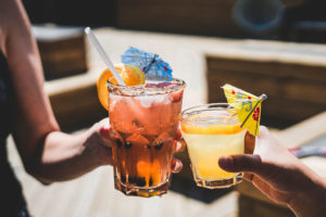 photo of two hands toasting summery cocktails