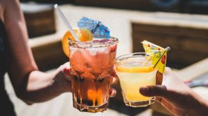 photo of two hands toasting summery cocktails