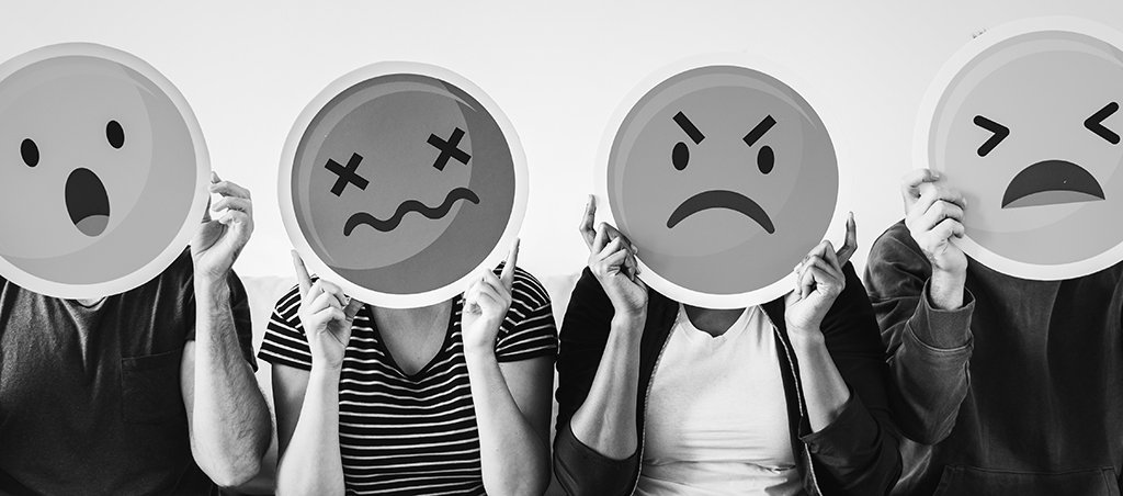 black and white photo of people holding upset emojis over their faces