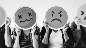 black and white photo of people holding upset emojis over their faces