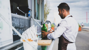 photo of a worker setting items on a food truck's fold down shelf