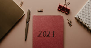 photo of a desk with office supplies and a red notebook with "2021" on the cover
