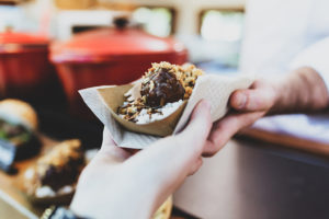 Close-up of a hand picking up meatballs from a food truck