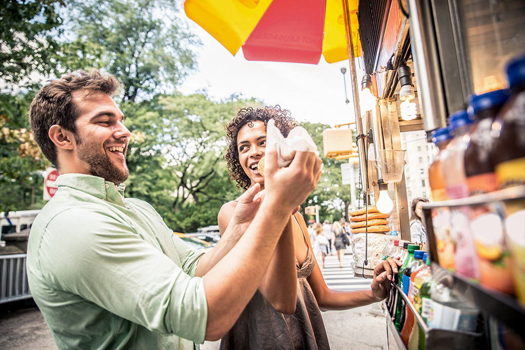 two people buying food from a food truck in the city