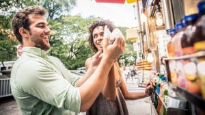 two people buying food from a food truck in the city