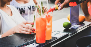 bartender pouring orange liquid into a cocktail glass