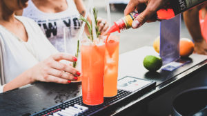 bartender pouring orange liquid into a cocktail glass