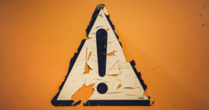 exclamation mark warning sign painted on an orange wall