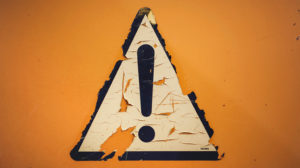 exclamation mark warning sign painted on an orange wall
