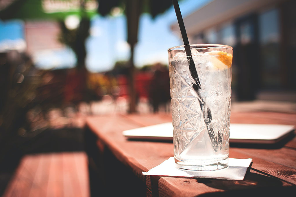 glass of ice water on a picnic table in the sun