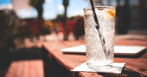 glass of ice water on a picnic table in the sun