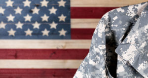 Close up of military uniform with painted rustic boards of USA flag in background.